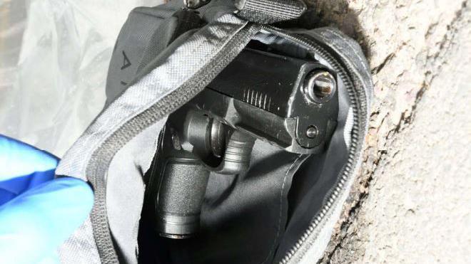 A close-up of a firearm in a bag that's zipped open.