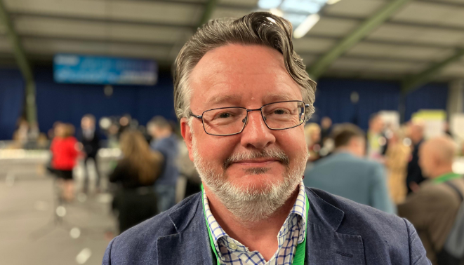 A man with a beard and glasses smiling