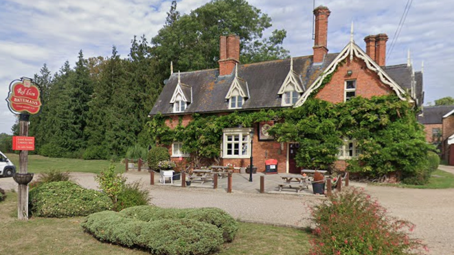 The Red Lion pub at Revesby. In front of the two-storey pub are various shrubs and a few benches. The front of the pub is covered in lush, green foliage.