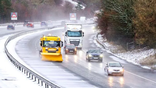 A yellow snowplough drives down a snowy M74 near Abington in South Lanarkshire on 26 December, 2022.