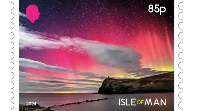 An Isle of Man 85p stamp with a pink-yellow hue northern lights seen in the skies above Bradda Head and Port Erin Bay. 