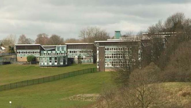 Several of Archbishop Temple School's buildings, standing on a hill with trees obscuring some of them