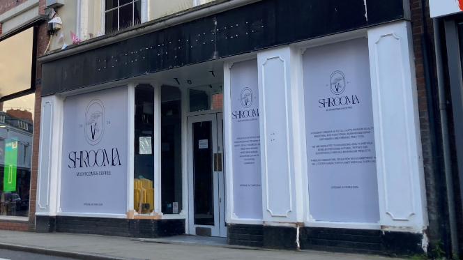 The front of a shop with white signs covering the windows with the word "Shrooma" and smaller writing on them