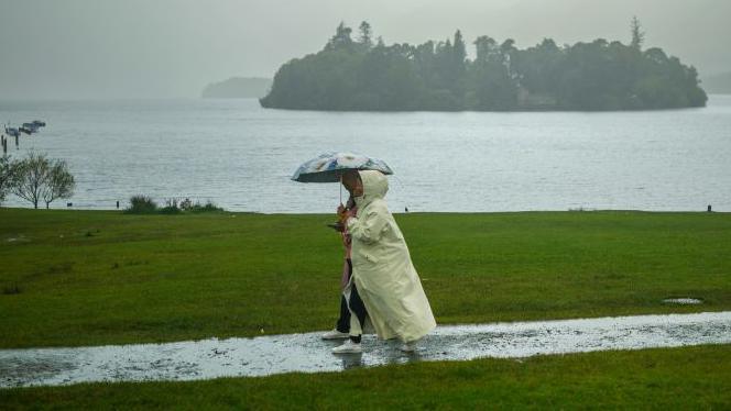 Two tourists brave heavy rain and low cloud at Derwentwater on August 27