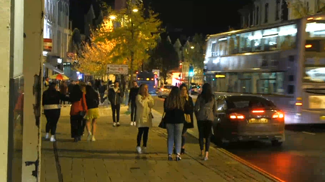 We can see people working and standing on Prince of Wales Road. In the background a bus is passing by.