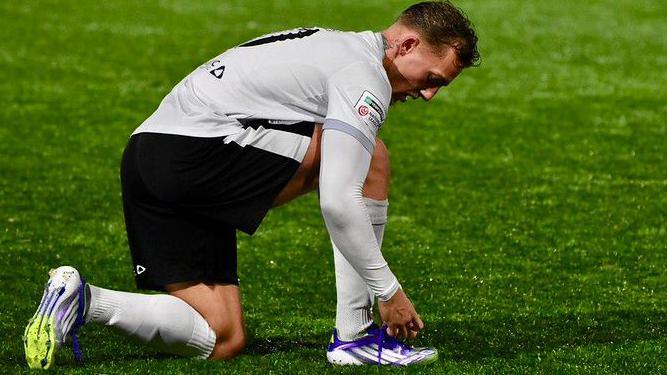 Merthyr Town striker Ricardo Rees tying the laces on his purple boots