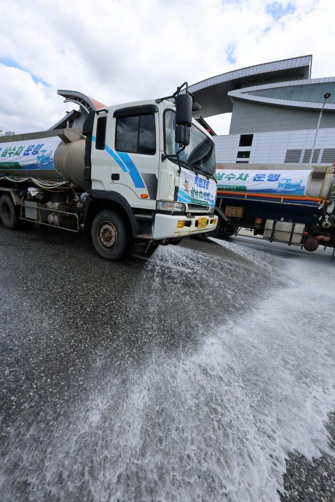 A sprinkler truck sprays water on the road