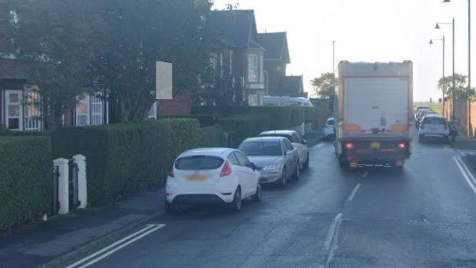 A lorry and parked cars on a sunny day
