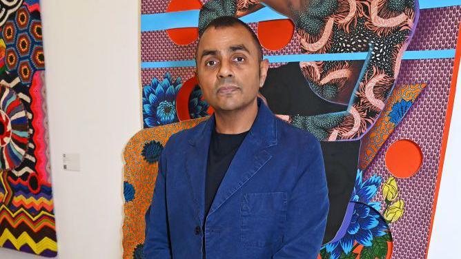 Waheed Alli standing in front of some artwork