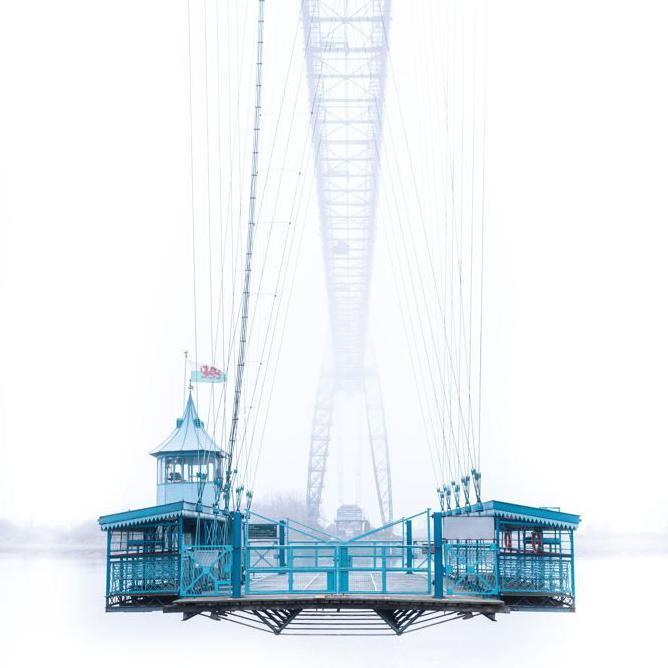 Newport transporter bridge in thick fog with gondola below and Welsh flag flying 