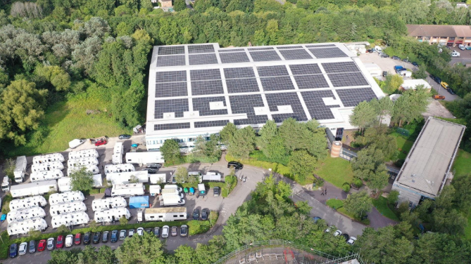 A view of The Bottle Yard Studios site from the air. It shows solar panels on the roof, trees, shrubbery and parked cars. 