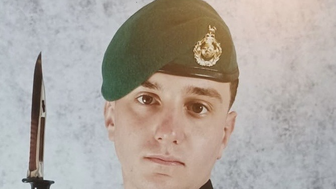 Image of Joshua Houghton in his Royal Marine Commando uniform. He is wearing a green military beret and staring solemnly into the camera