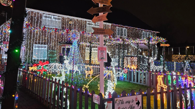 A snowy scene of a house covered in illuminations