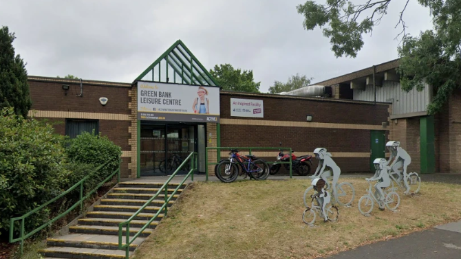 Steps leading up to brick leisure centre with metal sculptures of a family on bikes to the right of the image