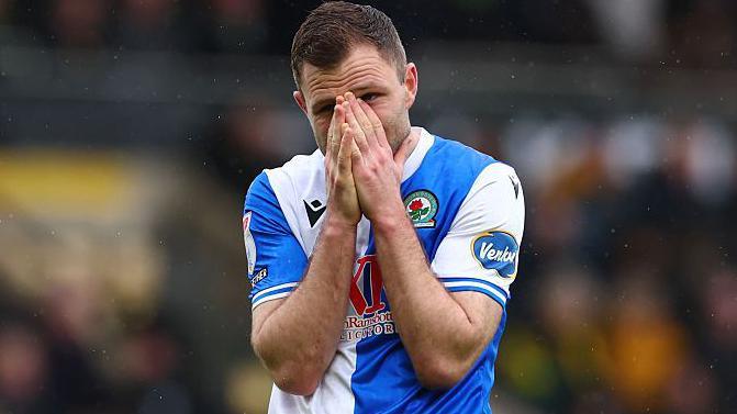Blackburn's Sondre Tronstad wearing a blue and white halved Rovers shirt with his hands over his face looking anguished