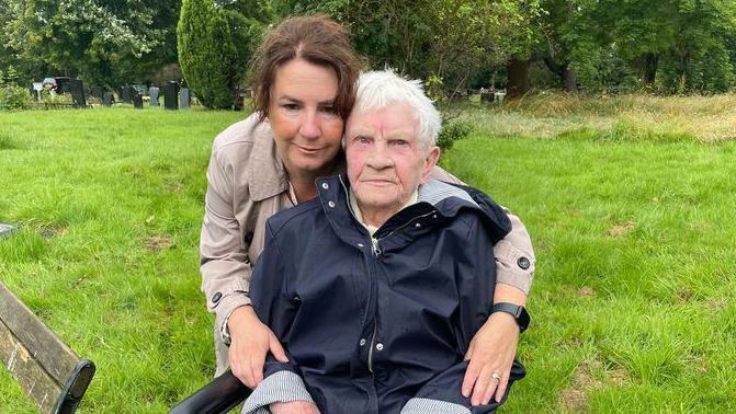 Jo Norton with her arms around her mother Betty Rawsthorne in a cemetery