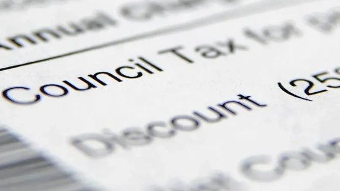 A blurred image of a council tax bill with black ink on white paper