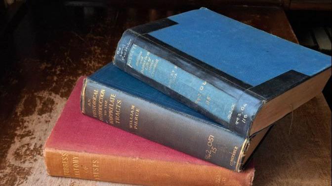 A stand of three books - one red and two dark blue.
