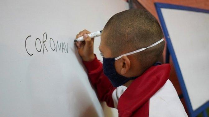 Student Juan Camacho writes the word "coronavirus" on a whiteboard during a lesson at Escuela 30, a rural school that has resumed classes after a month off due to the coronavirus disease (COVID-19), in San Jose, Uruguay April 22, 2020