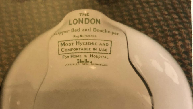 An old image of a Shelley-made white porcelain bedpan. It shows the Shelley brand logo, as well as some written explanation that the bedpan could be used both in the home and hospital. 