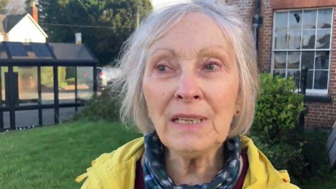 Janette Ward, wearing a yellow jacket, stands in front of her local bus stop which she uses to catch services to see her daughter and go to appointments