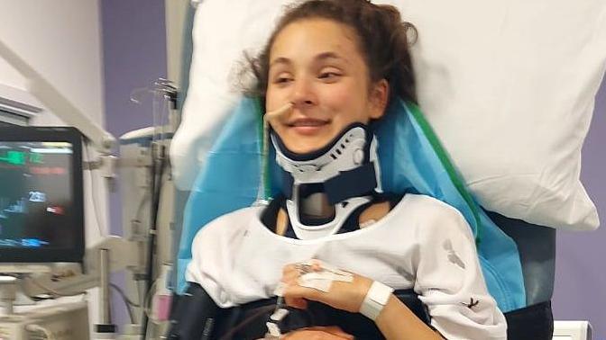 Paulina sits upright in a hospital bed with a brace around her neck.