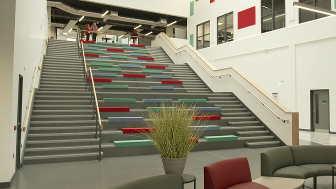 A large, wide stair case can be seen with red, blue and green cushions positioned in the middle.