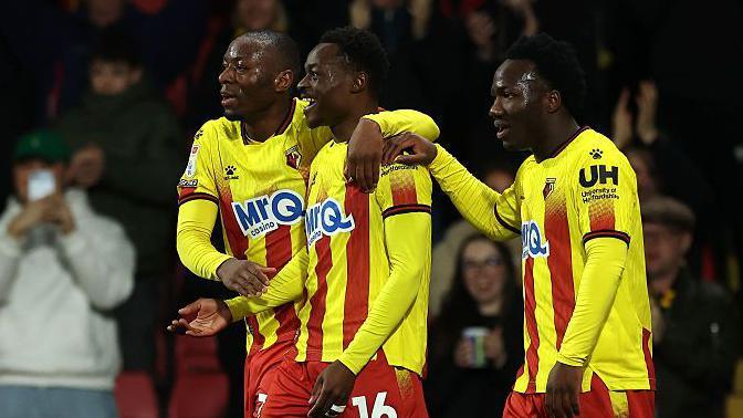 Marc Bola of Watford (centre) celebrates scoring against Wrexham with team-mates Nestory Irankunda (right) and Edo Kayembe (left)