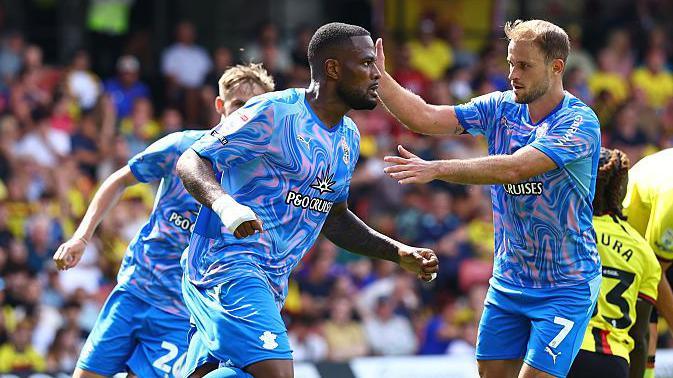 Cyle Larin celebrates with Leo Scienza after scoring against Watford, wearing the pink and blue Saints away kit