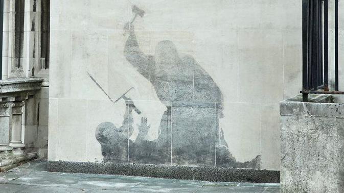 Banksy mural of a judge attacking a protestor with a gavel. The painting has been washed away, so the details are not visible, leaving a grey shadowy silhouette.
