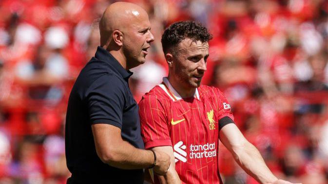 Arne Slot with Diogo Jota on the touchline during a game.