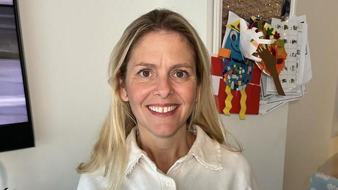 Lucy stands in her kitchen/diner in Holborough Lakes. She has long, blonde hair and is smiling at the camera.