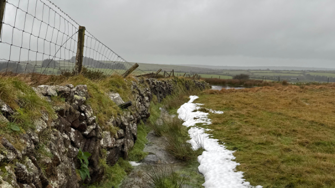 St Breward with a bit of snow. Moorland and a stone wall pictured in gloomy conditions