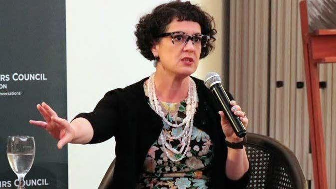  Professor Laura Murphy speaks at an event. she is sitting down and holding a microphone 