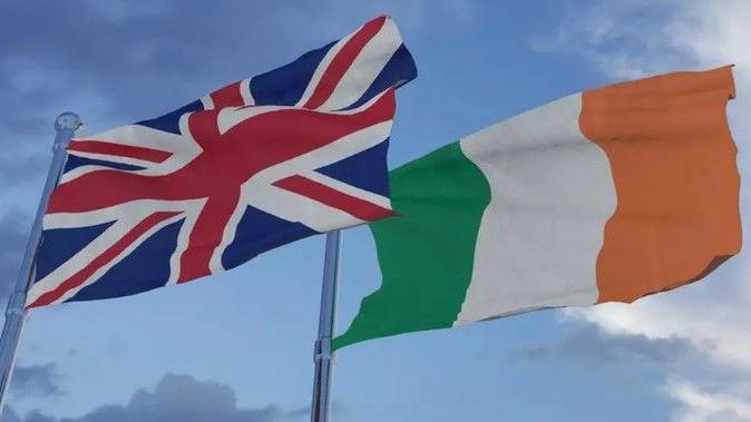 A Union flag and Irish tricolour flying beside each other on separate flag poles