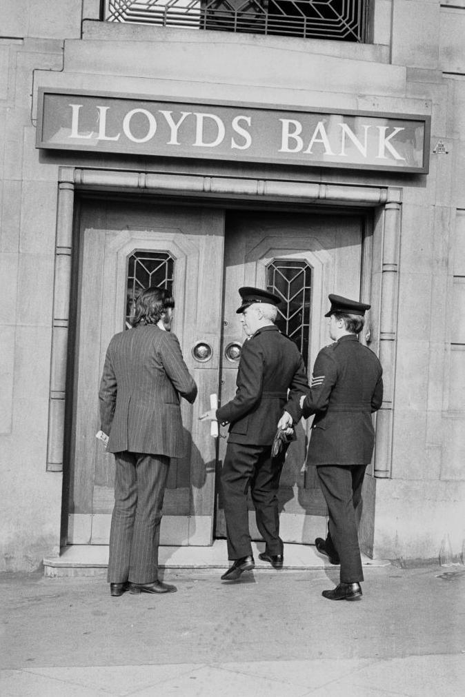 Black and white archive image, showing Lloyds Bank and detectives and uniformed officers entering the bank 