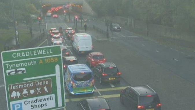 Traffic waiting at the road with a sign saying Cradlewell. The other lane is closed.