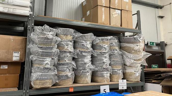 A picture of woven baskets stacked up on shelves in a warehouse 