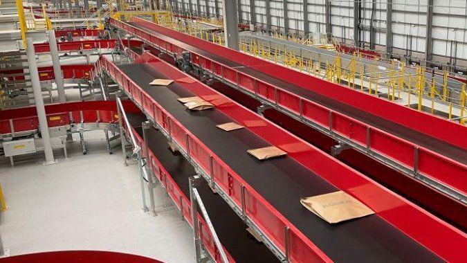 Red and black conveyor belt with parcels at regular intervals