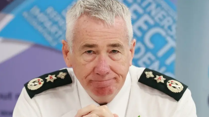 Jon Boutcher pictured in uniform, his hands are clasped and he is staring forward.