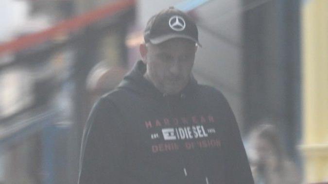 Image of Arsen Feci under survaillance. He is wearing a Diesel hoody and a Mercedes baseball cap. 