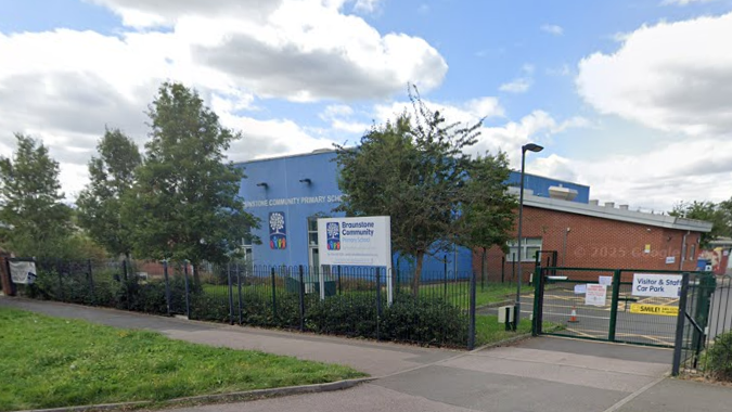 A street view image of Braunstone Community Primary School, with a pavement and fence in front of a blue school building
