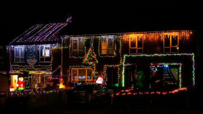 A row of terrace house with coloured Christmas lights on them 