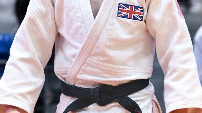 A judoka gi with a black belt around the waist and a Union Jack on the chest