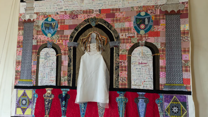 A colourful embroided woman, placed on a large sheet of fabric inside Hardwick Hall in Derbyshire.