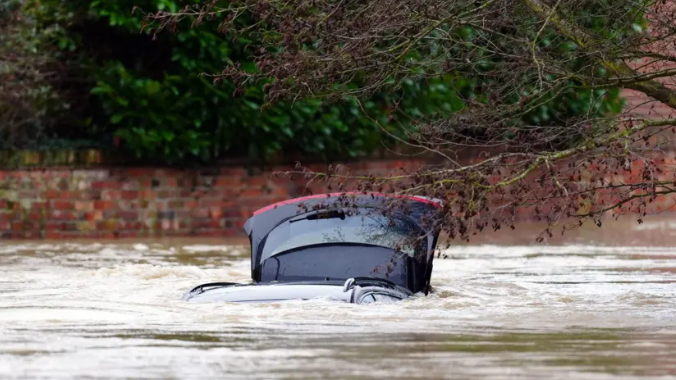 A car with its boot open almost entirely submerged in water