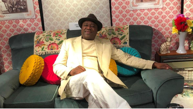 Man sat on the sofa wearing a hat.