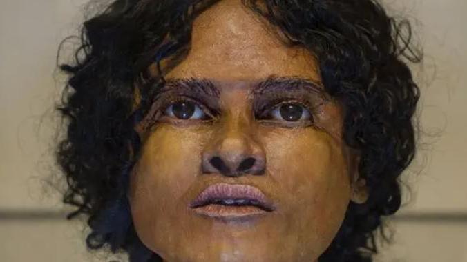 A woman. She has black curly hair and brown eyes. 