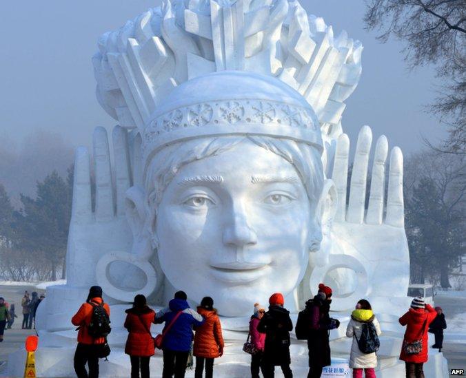 A giant sculpture of a face with two raised hands either side