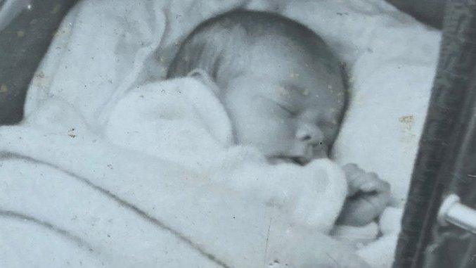 black and white photo of a baby in a crib